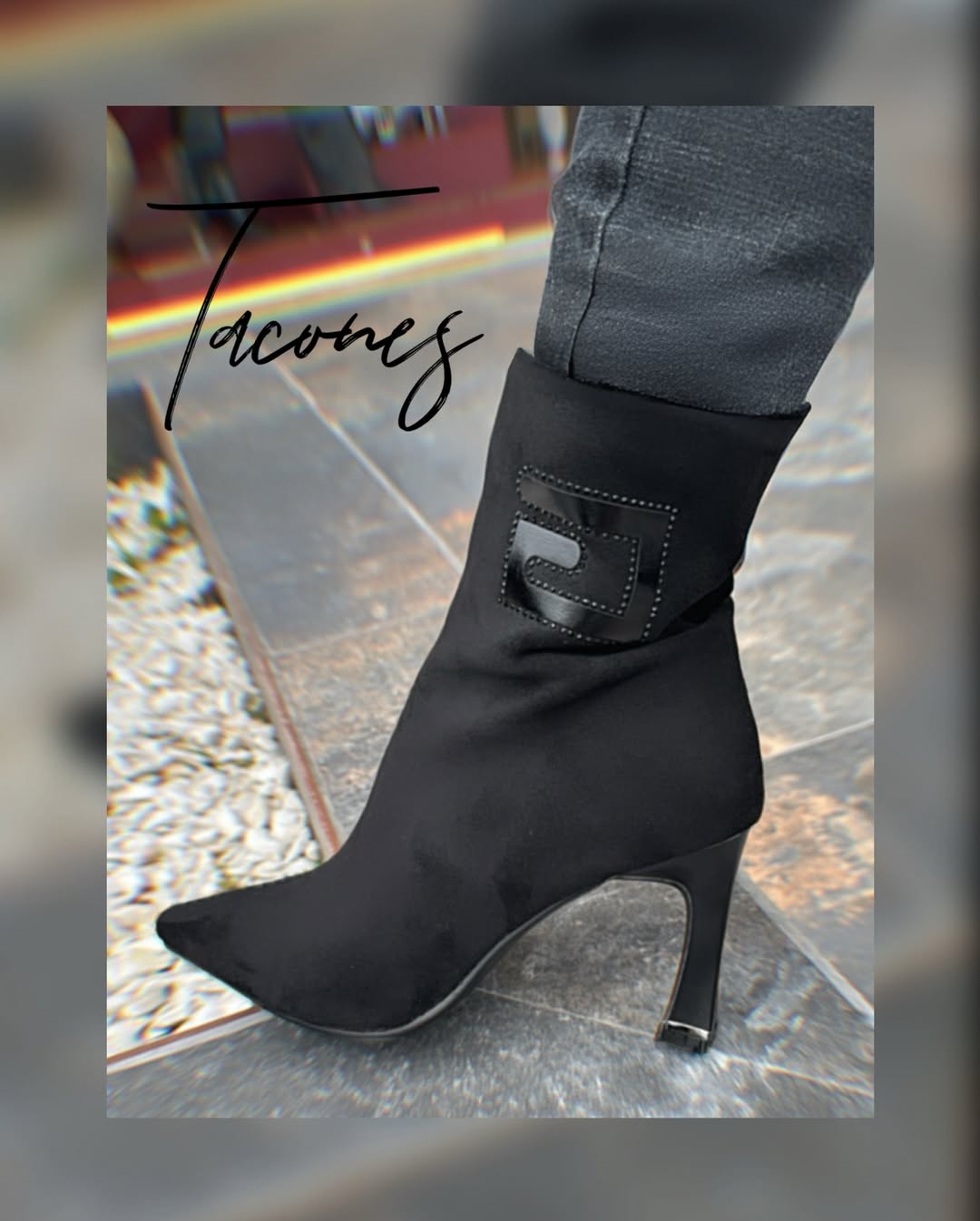 Botín en suede negro con punta fina, tacón estilizado y detalle de parche brillante en el lateral.